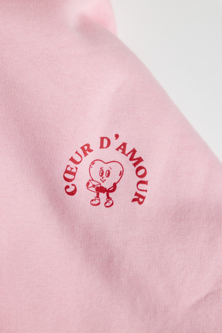 Close-up des "Coeur d'Amour" Logos in Rot auf rosanem Textil