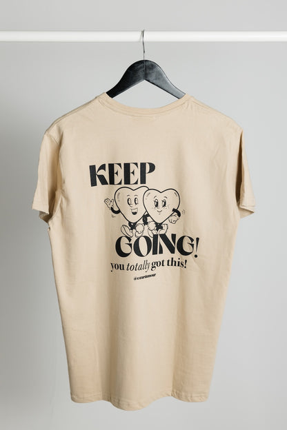 beiges Oversize T-Shirt mit schwarzem "KEEP GOING! you totally got this" Backprint, hängt an einem Kleiderbügel vor neutralem Hintergrund.