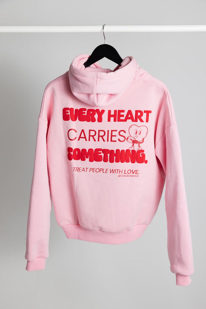  Oversize Hoodie mit rotem Backprint "Every Heart carries something" hängt an einem Kleiderbügel vor neutralem Hintergrund.