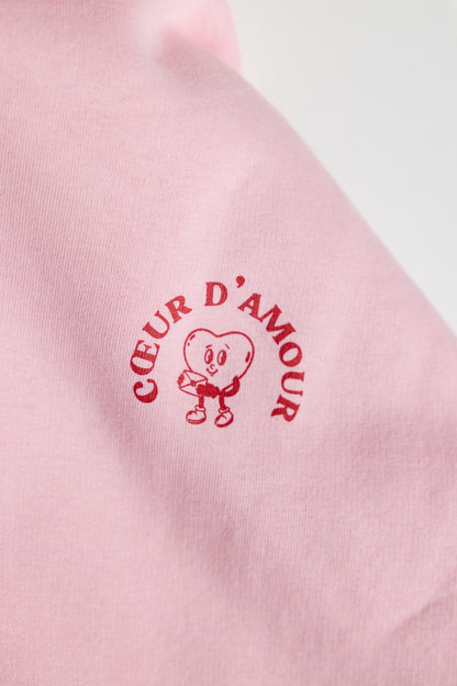 Close-up des "Coeur d'Amour" Logos in Rot auf rosanem Textil